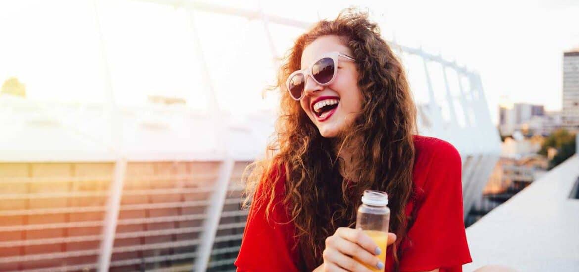 Happy Young Female Holding Juice Bottle and Sitting on Terrace | Smile Virtual
