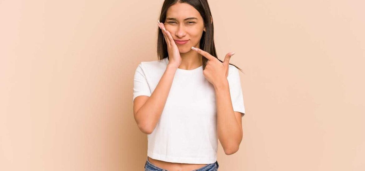 Young Girl With Her Hand Held To Her Face With Painful Expression Showing Toothache | Smile Virtual