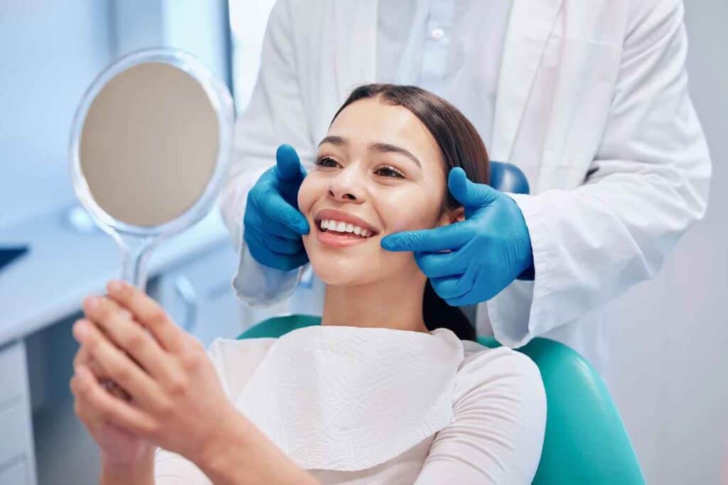 Female Patient Looking Teeth In Mirror At Dental Clinic | Smile Virtual
